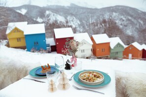 A table set with plates, glasses, and cutlery, with a bowl of food and a vase of flowers. - Iskö Chalets-hötel (Eaux-Bonnes)
