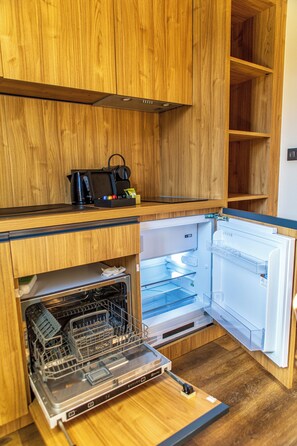 Une cuisine compacte avec des meubles en bois, un lave-vaisselle intégré et un réfrigérateur.