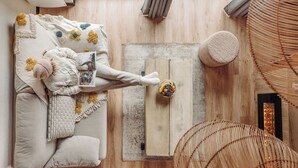A top-down view of a cozy room with a bed, a wooden floor, a small table with a fruit bowl, and a woven chair. - Iskö Chalets-hötel (Eaux-Bonnes)
