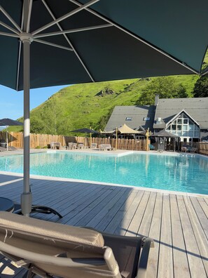 A pool area with wooden deck, lounge chairs, and umbrellas. - Iskö Chalets-hötel (Eaux-Bonnes)