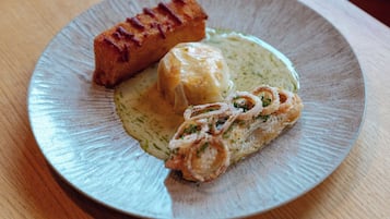 A plate with a piece of grilled meat, a dumpling, and a rolled omelette on a ceramic plate.