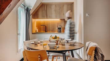 Una cocina moderna con armarios de madera, una cafetera y una mesa de comedor lista para el desayuno.