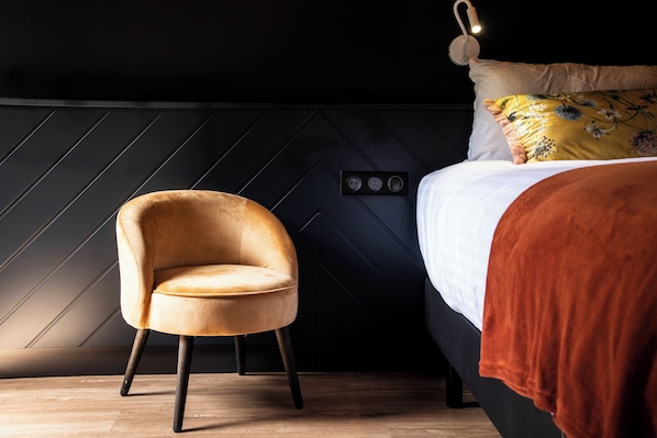 A modern room with a bed, a chair, and a wall with a geometric pattern.