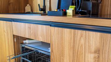 Una cocina compacta con armarios de madera, lavavajillas integrado y cafetera.