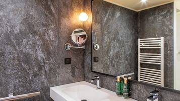 Une salle de bain moderne avec un grand miroir, un lavabo blanc et un porte-serviettes.