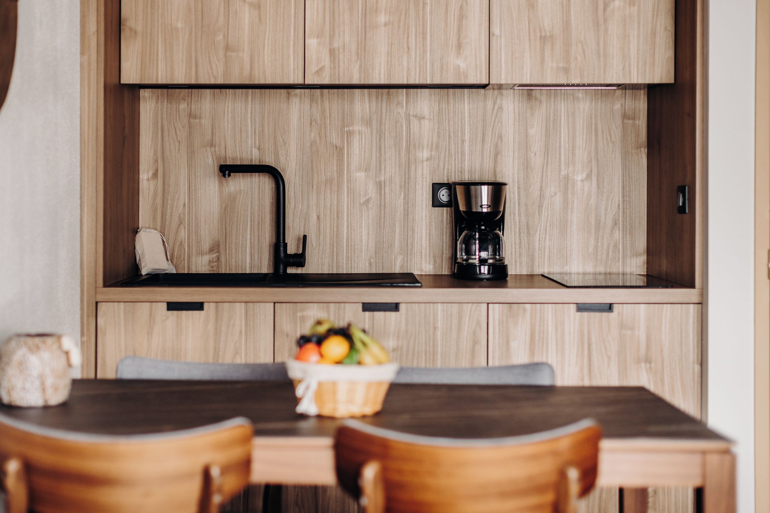 A modern kitchen with wooden cabinets, a black faucet, and a coffee maker.