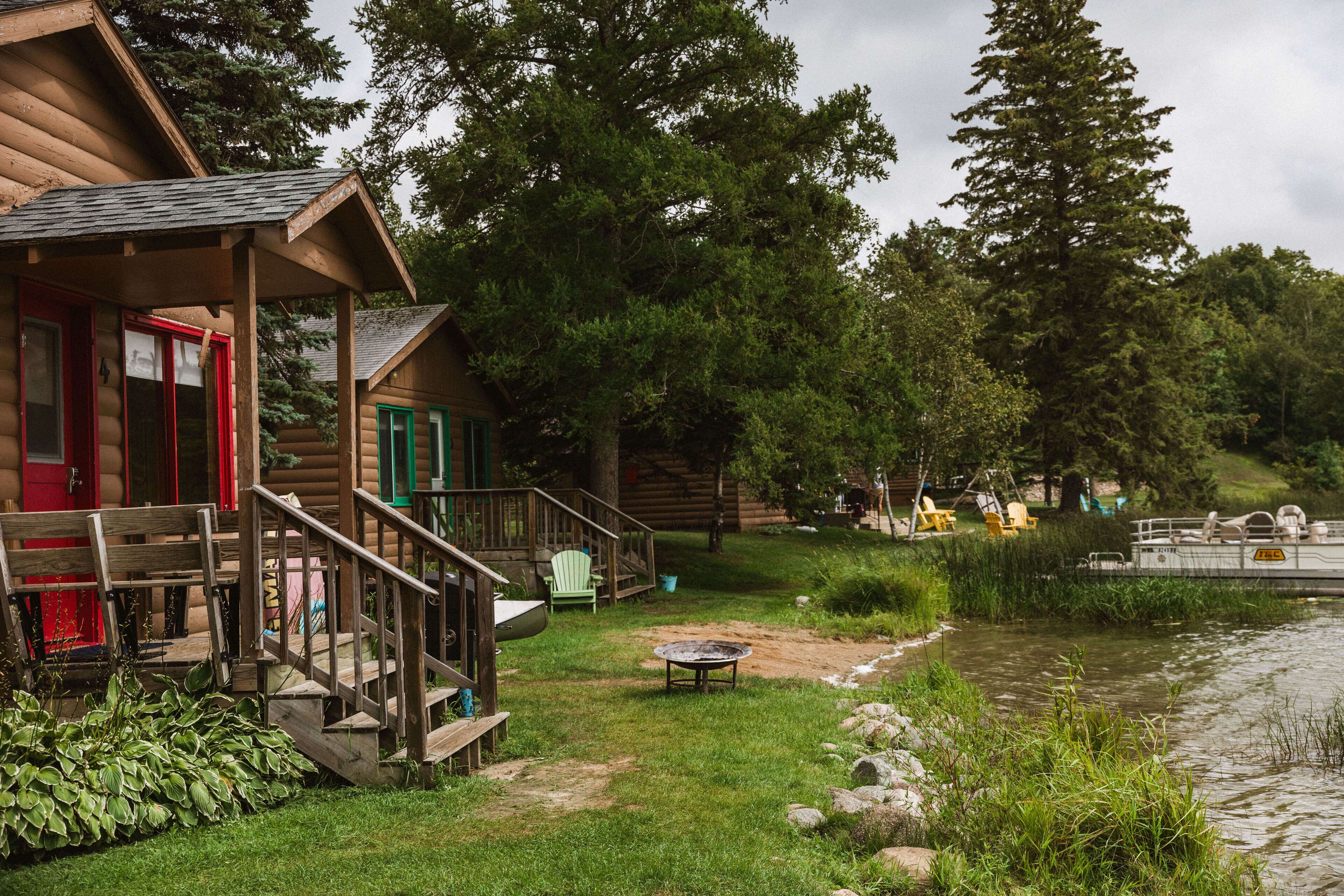 A cabin with a porch, a fire pit, and a dock extending into a lake.