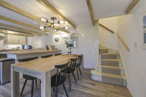 A modern kitchen with a wooden table and chairs, a built-in oven, and a staircase leading to an upper level.