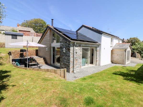 A two-story house with a stone exterior, a solar panel roof, and a small attached garage.
