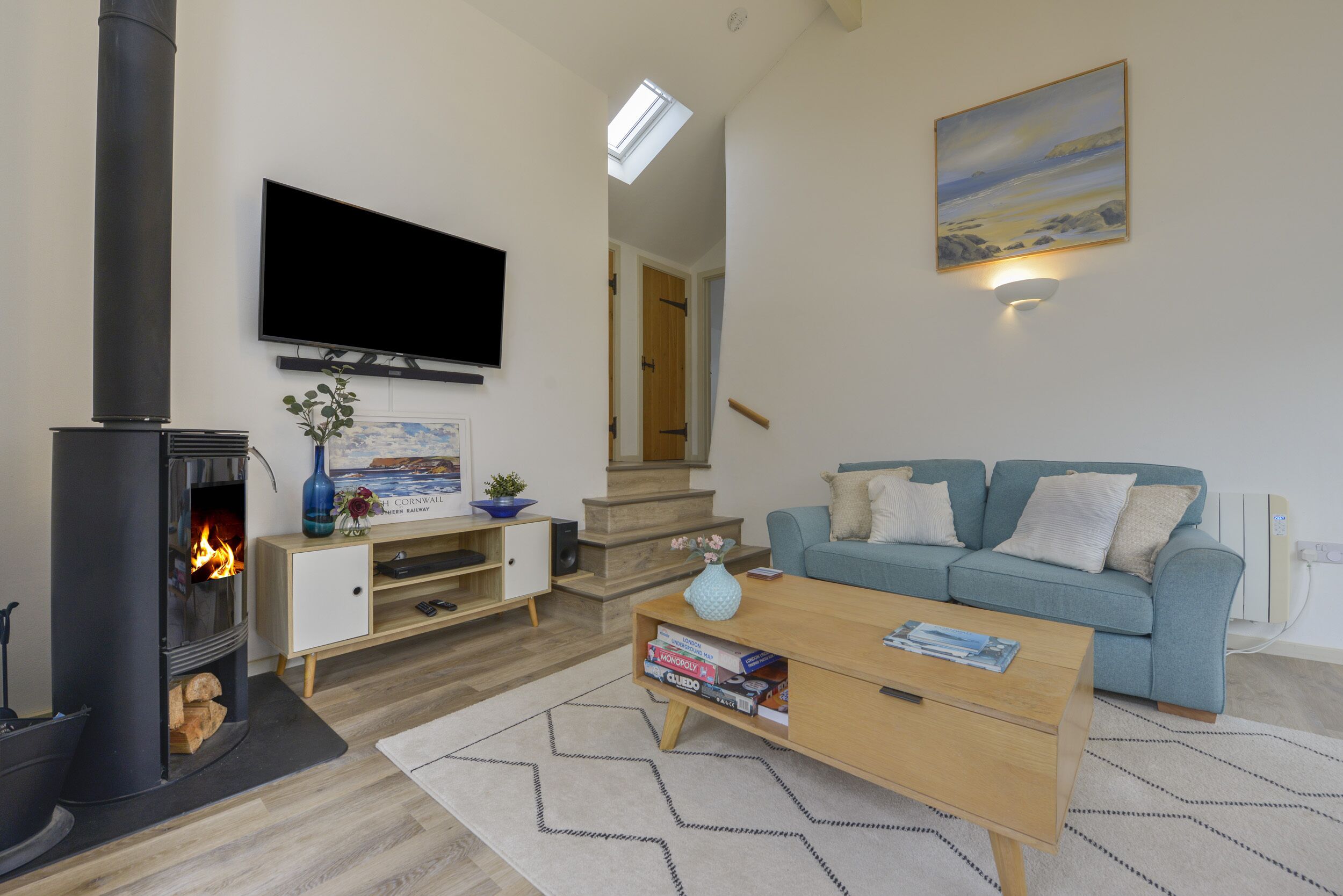 A living room with a fireplace, a sofa, a coffee table, and a TV mounted on the wall.