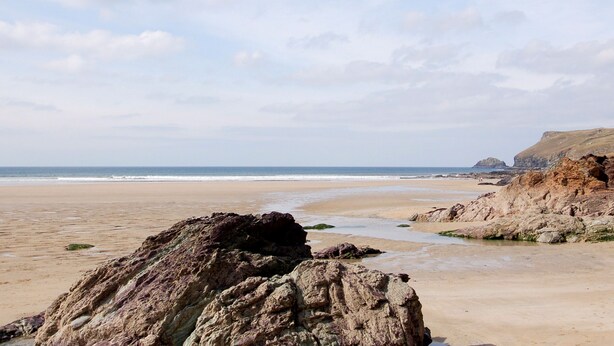 A beach with rocky outcrops and a clear sky. - Kelmscot (Port Isaac)