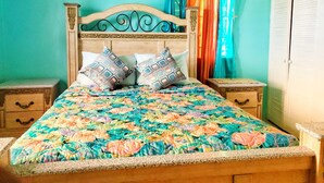 A bedroom with a wooden bed, floral bedspread, two nightstands, a small chest of drawers, a framed picture on the wall, and teal walls. - 2 Bed-sleeps 4-gated Community-5 Min Town Centre (Falmouth)