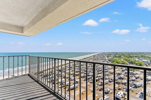 A balcony with a view of a beach and RV parking lot.