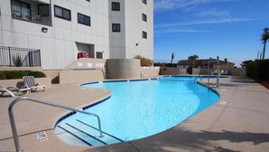 A swimming pool with a curved edge, surrounded by a concrete deck. There are lounge chairs and a lifeguard chair near the pool. - MB Renaissance 1516- 2BR/2BA Oceanfront Condo in Myrtle Beach (Myrtle Beach)