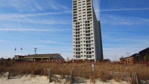 A tall, rectangular building with multiple floors and a flat roof, surrounded by sandy terrain and sparse vegetation. - MB Renaissance 1516- 2BR/2BA Oceanfront Condo in Myrtle Beach (Myrtle Beach)