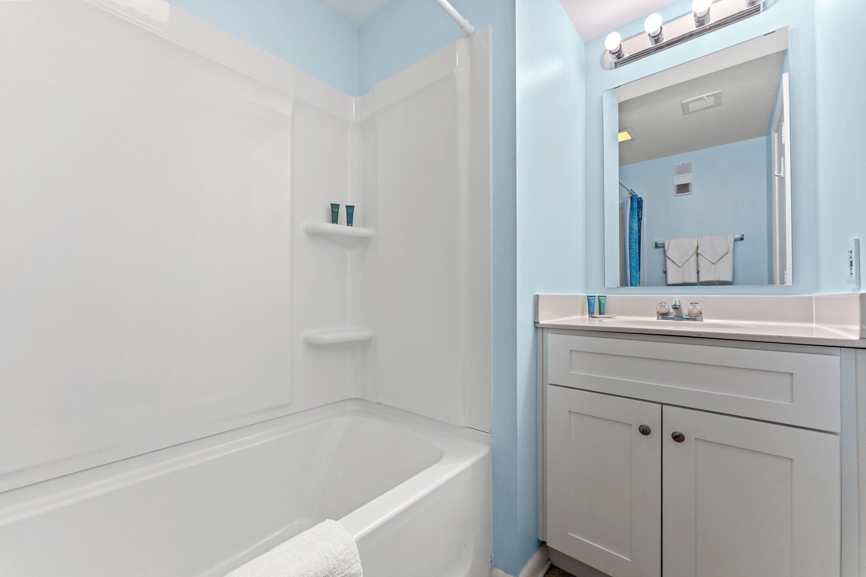 Une salle de bain équipée d’une baignoire, d’une douche, d’un meuble-lavabo avec un miroir et d’un porte-serviettes.