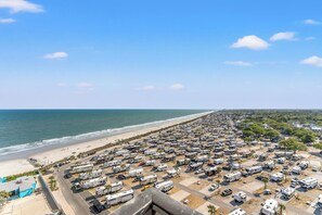 A large RV parking area adjacent to a beach with ocean views.