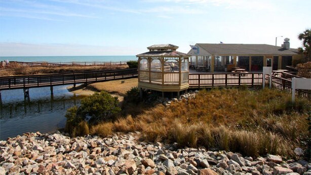 A coastal area with a wooden gazebo, a bridge, and a building with a deck overlooking the beach. - MB Renaissance 1516- 2BR/2BA Oceanfront Condo in Myrtle Beach (Myrtle Beach)
