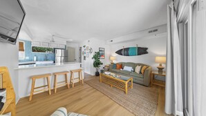 Una sala de estar moderna con un sofá, una mesa de centro y una zona de cocina al fondo.
