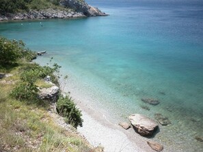 Enjoy a serene beach experience with a gently curved shoreline and a natural barrier of rocky outcrops.