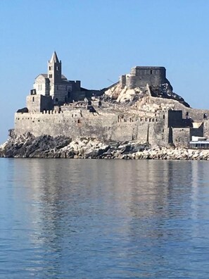 Un château historique en pierre, doté d’une tour imposante, situé sur une côte rocheuse, avec des eaux calmes en premier plan.