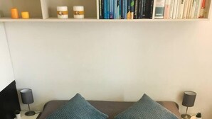 A neatly made bed with a grey quilt, two pillows, a tray with two cups and a rose, and a bookshelf in the background. - Cute 1 Bedroom Apartment in La Spezia (La Spezia)