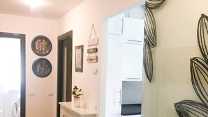 A hallway with a white cabinet, a small plant, and wall decorations. There is a door leading to a kitchen area. - Cute 1 Bedroom Apartment in La Spezia (La Spezia)