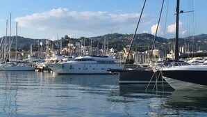A marina with multiple yachts docked, calm water, and a hilly town in the background. - Cute 1 Bedroom Apartment in La Spezia (La Spezia)