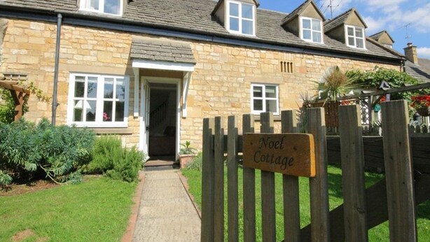 A stone cottage with a wooden gate labeled "Noel Cottage." - Noel Cottage (Chipping Campden)