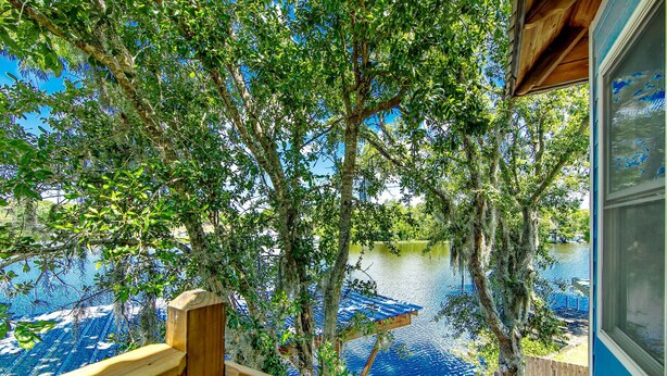 Eine Holzterrasse mit Blick auf einen See, Bäume und einen wolkenlosen, blauen Himmel.