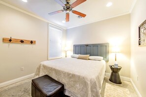 Une chambre à coucher avec un lit, un ventilateur de plafond, une table de chevet avec une lampe et un banc.
