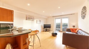 Enjoy a spacious living area with a kitchen, dining table, and comfortable sofa, plus a balcony with a view.