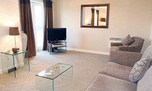 Relax in this stylish living room with a flat-screen TV, comfortable sofa, and decorative coffee table.