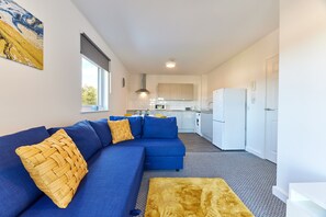 Relax in a stylish living area with a blue sofa, plush ottoman, and abstract art.
