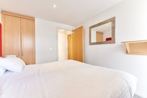 Relax in a spacious room with a large bed, wardrobe, and mirror.