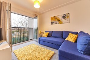 Relax in a stylish living room with a sofa, balcony views, and a unique piece of art.