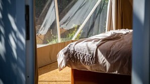 Een kamer met een bed, een raam en uitzicht op groen.