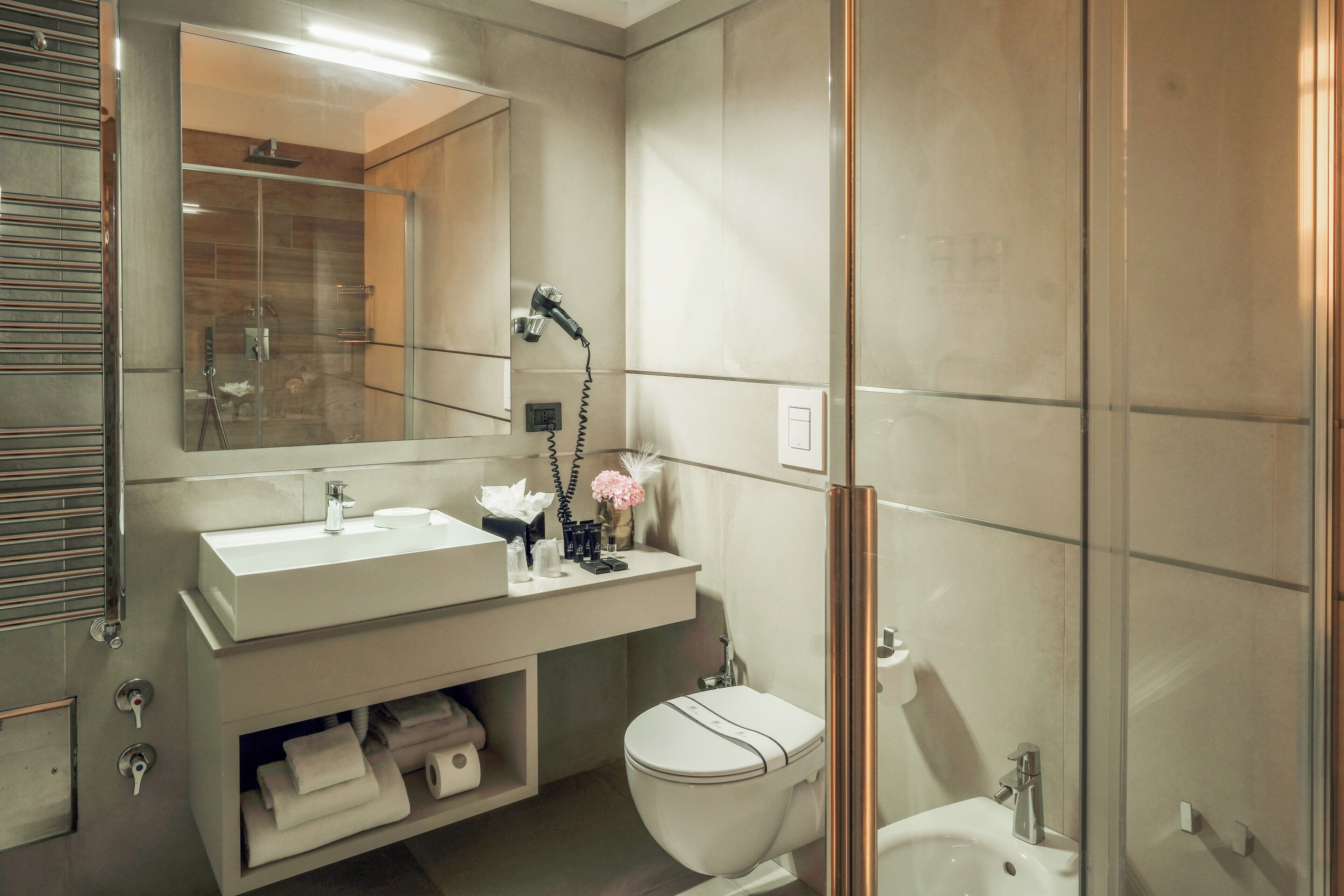 A modern bathroom with a glass shower enclosure, a white sink, and a toilet.