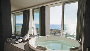 Une salle de bain moderne dotée d’une grande baignoire, d’un meuble-lavabo et offrant une vue sur la mer.
