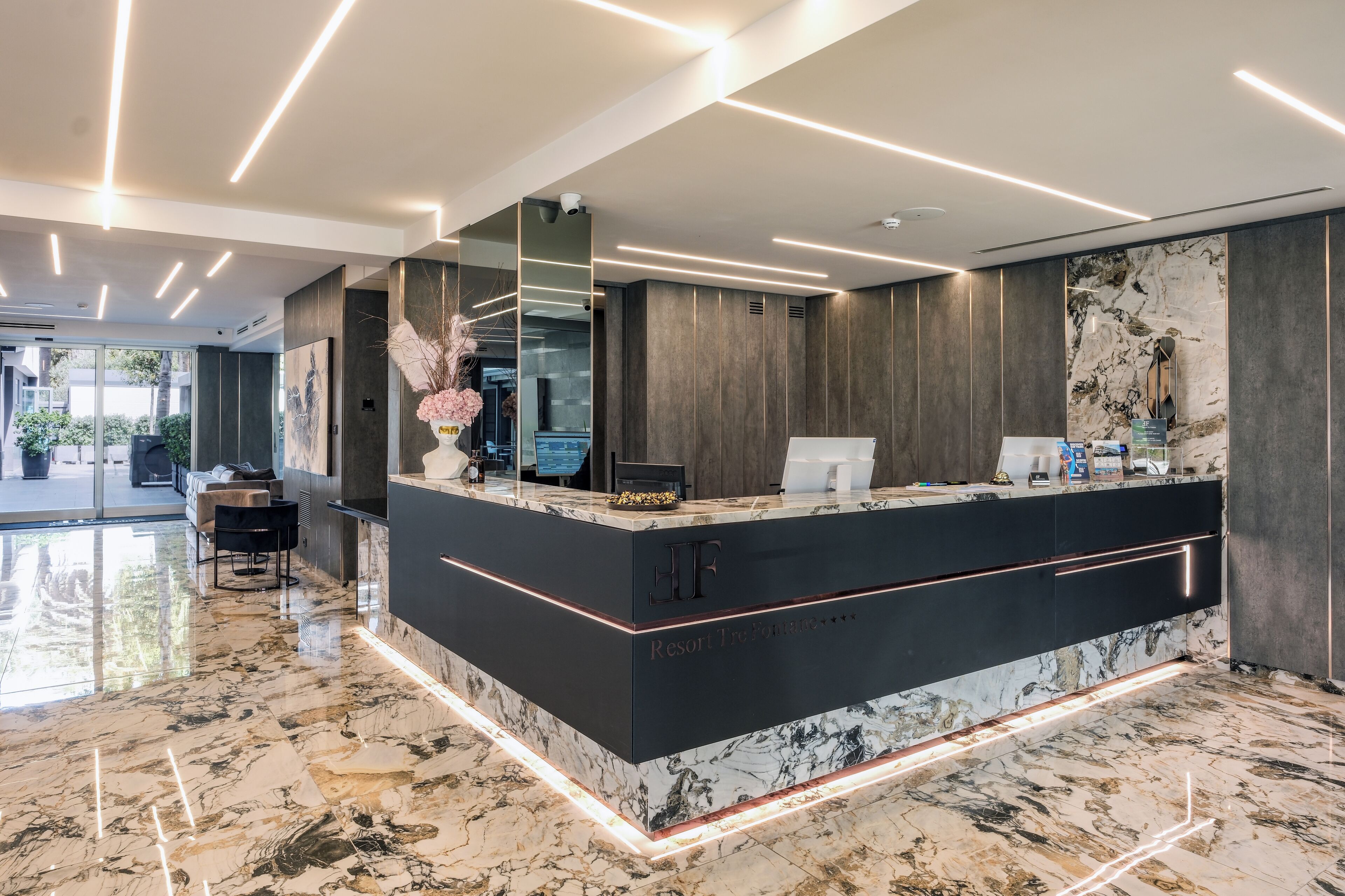 Un moderno mostrador de recepción con piso de mármol, una barra negra y un espejo grande.
