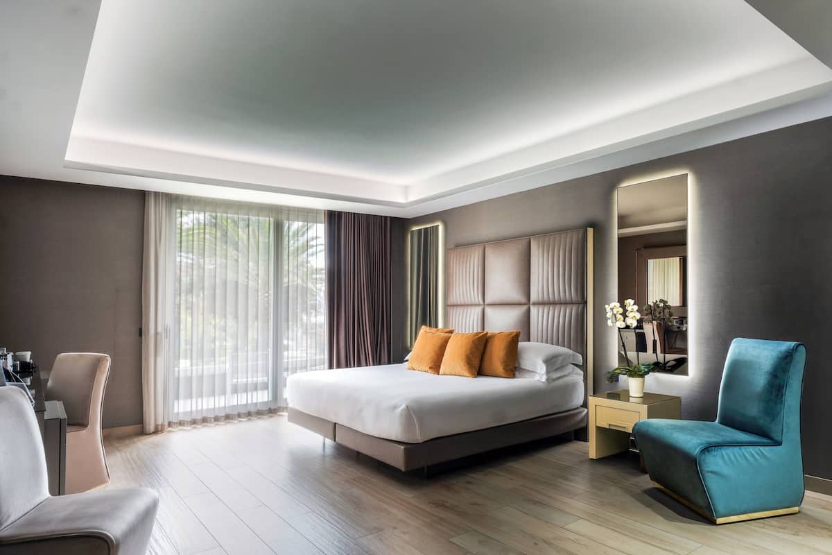 Ein modernes Hotelzimmer mit einem großen Bett, einer Sitzecke und einem Spiegel.