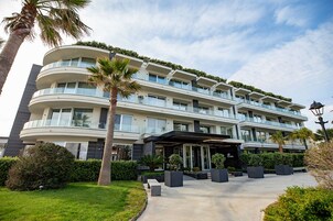 Un hotel de varios pisos con fachada curva, balcones y un área de entrada cubierta.