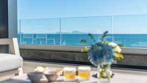 A balcony with a view of the sea, a table with drinks and a bowl, and a vase with flowers. - Hotel & Resort Tre Fontane Luxury (Portici)