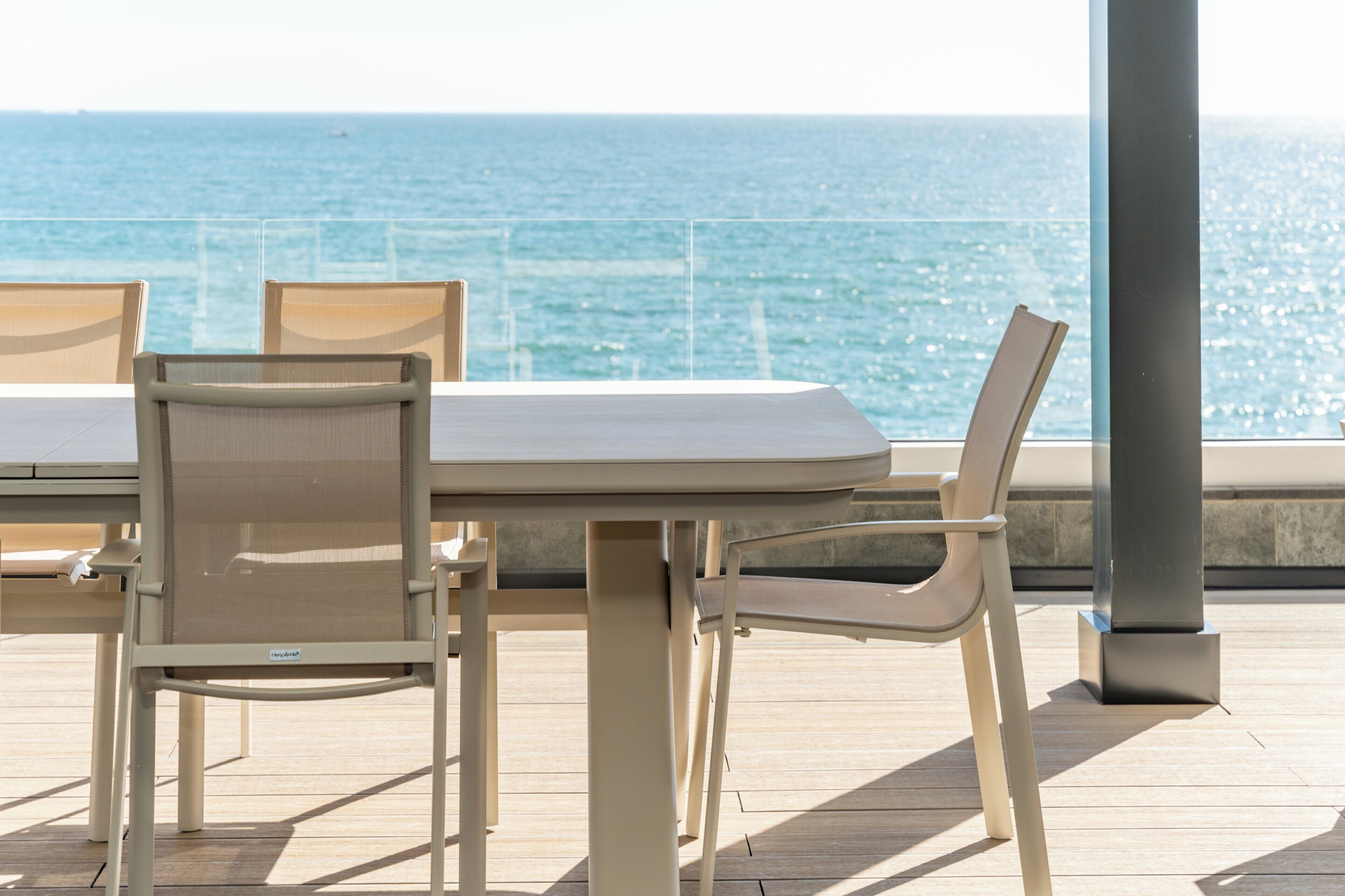 Ein Tisch und Stühle auf einer Terrasse mit Blick auf das Meer.