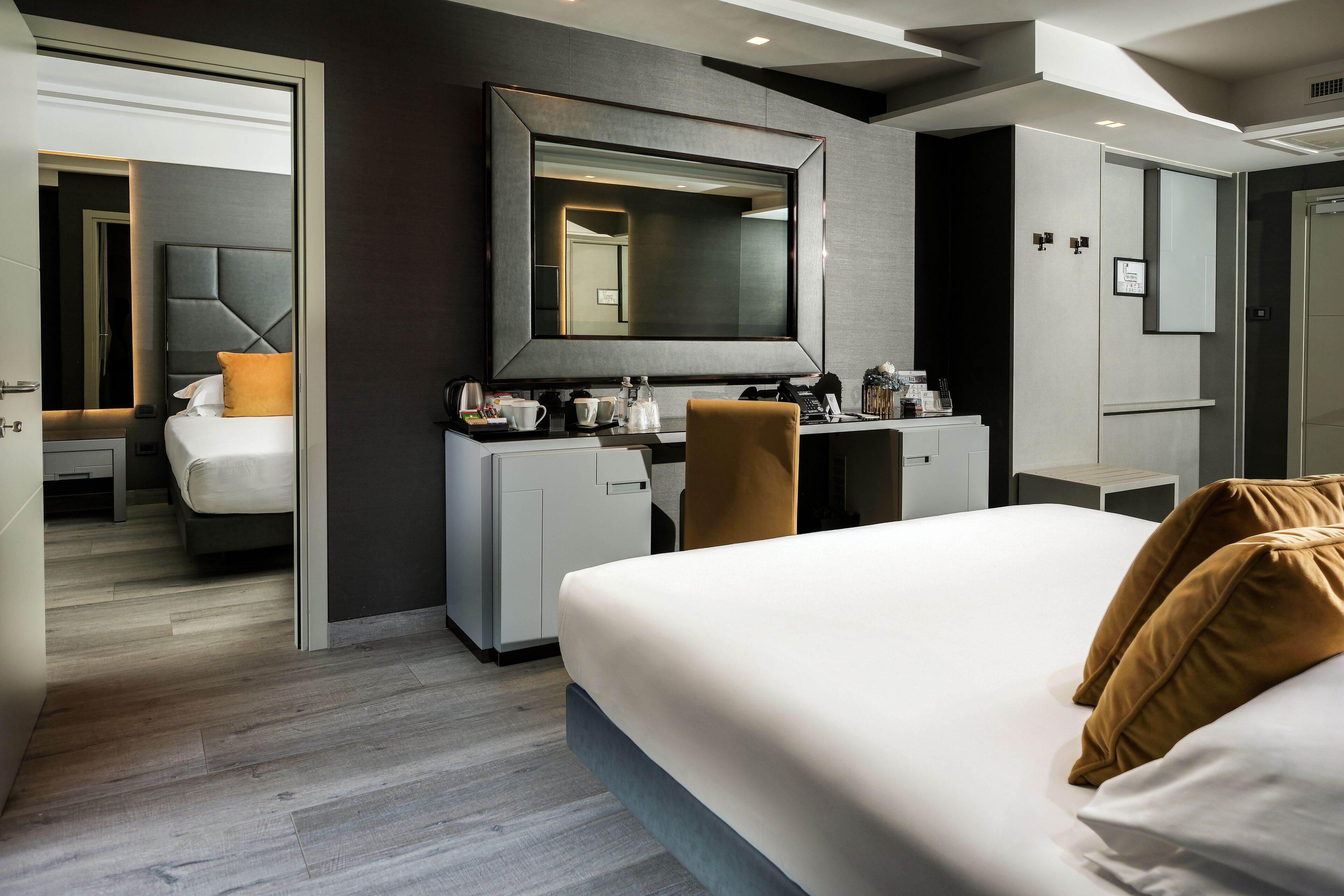 Una habitación de hotel moderna con una cama grande, un escritorio, una silla, un espejo y un armario.