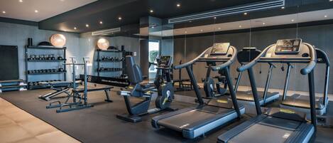 A modern gym with treadmills, elliptical machines, and free weights.