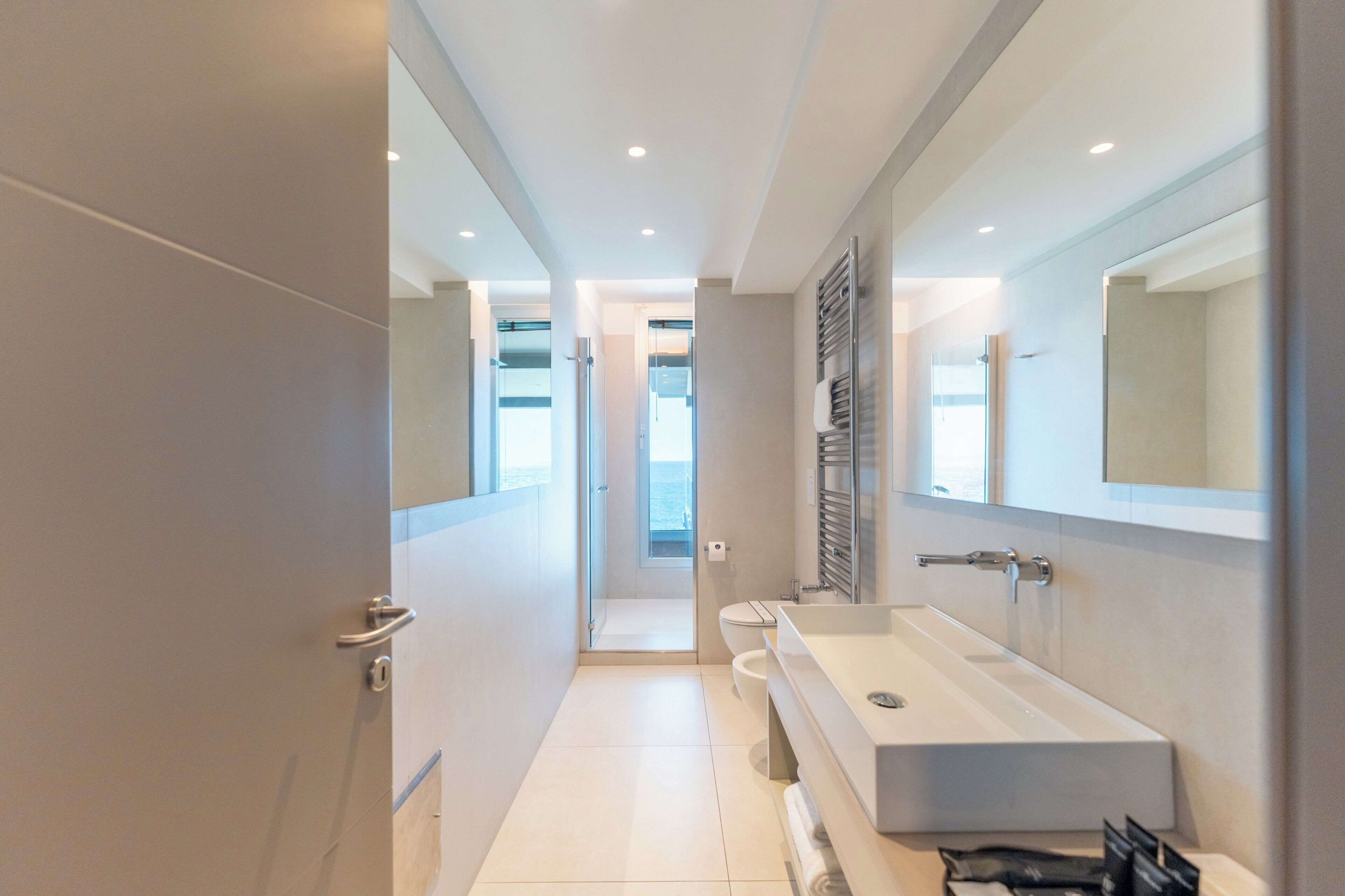 Een moderne badkamer met een grote spiegel, een witte wastafel en een douchehoek.