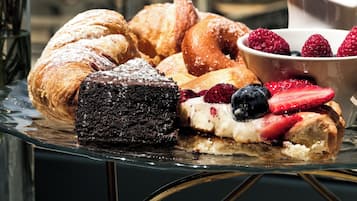 Un plateau de desserts avec des pâtisseries et des fruits rouges, posé sur une table en verre offrant une vue sur la mer.