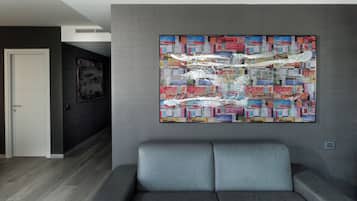 Ein moderner Wartebereich mit einem grauen Sofa, einem farbenfrohen abstrakten Gemälde an der Wand und einer Tür im Hintergrund.