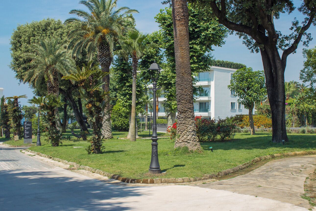 Un parc bien entretenu, avec des palmiers, un lampadaire et un bâtiment en arrière-plan.